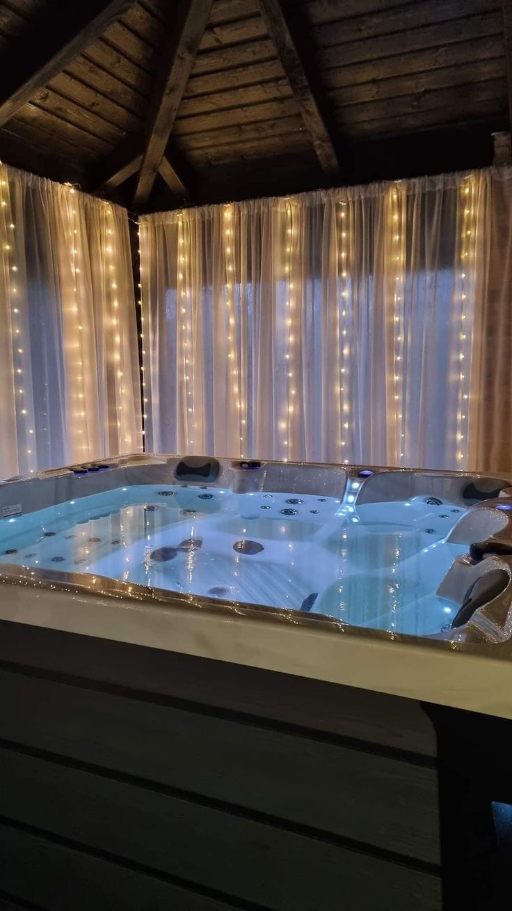 an indoor jacuzzi with lights on the ceiling and curtains in the back ground