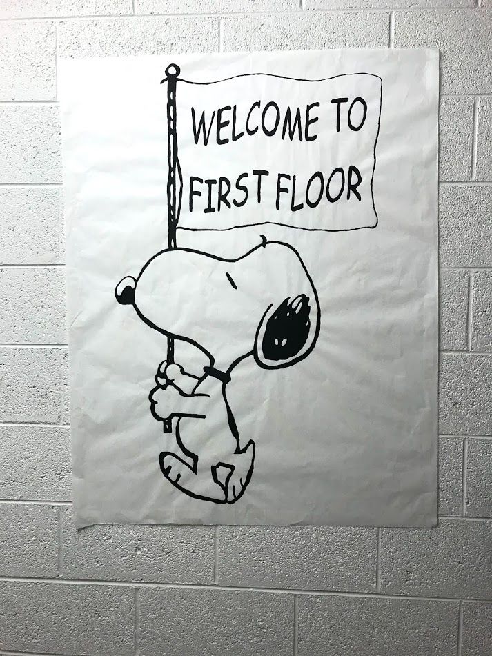 a sign that says welcome to first floor with a cartoon dog holding a flag in front of it