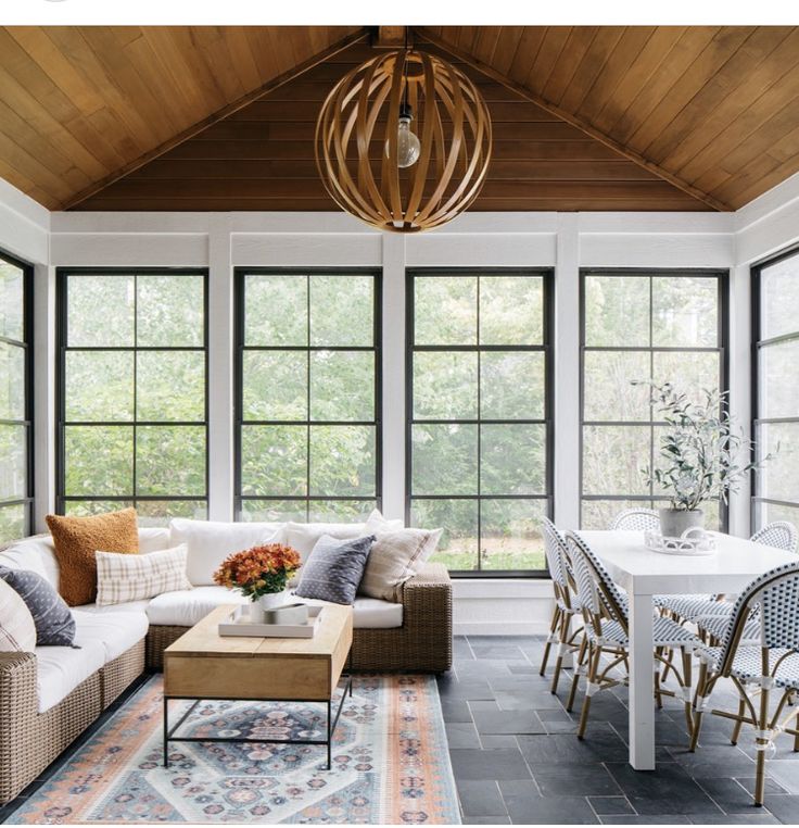 a living room filled with furniture and windows next to a dining table in front of a large window