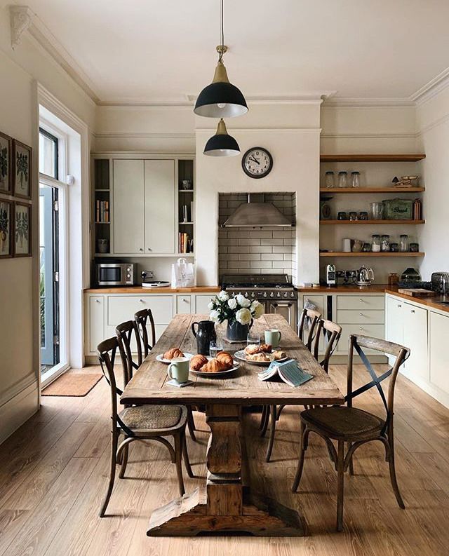 a dining room table with chairs and a clock on the wall in front of it