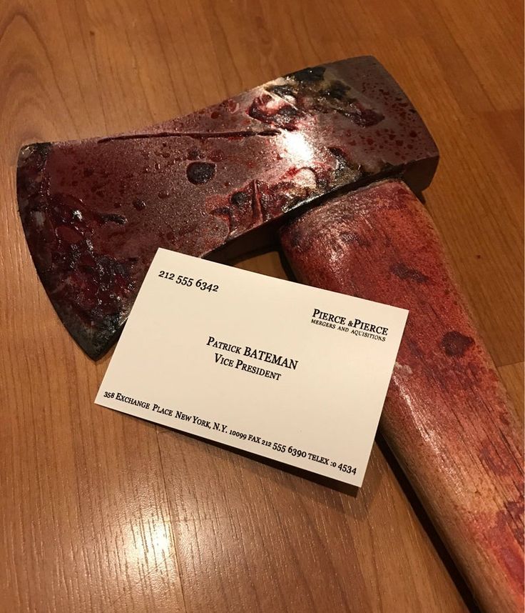 a hammer and business card sitting on top of a wooden table next to a knife