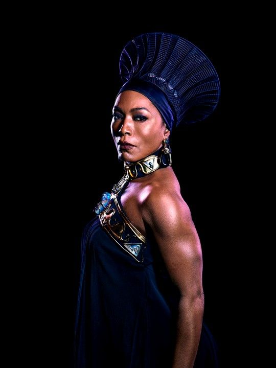 a woman wearing a headdress and jewelry in front of a black background with her hands on her hips