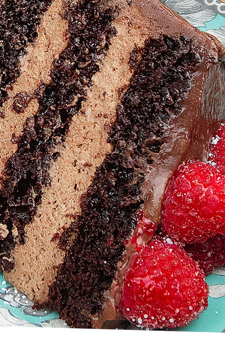 a piece of chocolate cake on a plate with raspberries