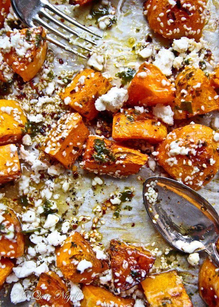 a pan filled with sweet potatoes covered in feta cheese and seasoning next to a fork