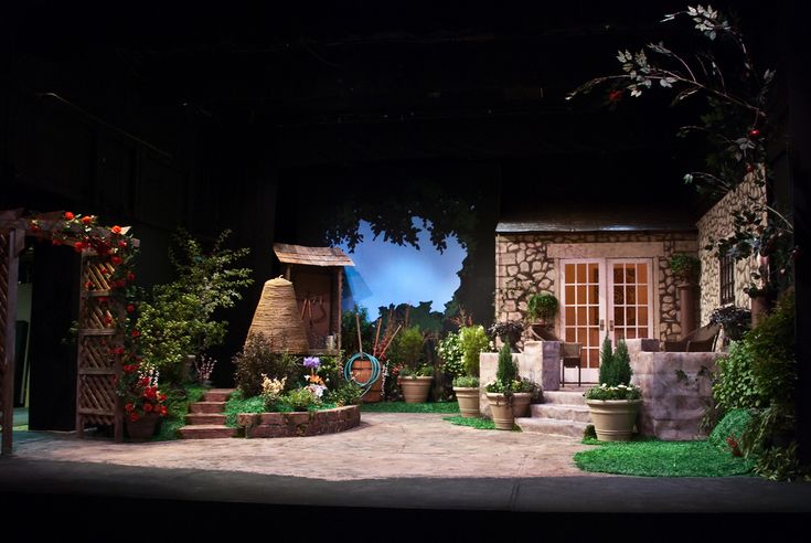 an outdoor stage set with potted plants and flowers