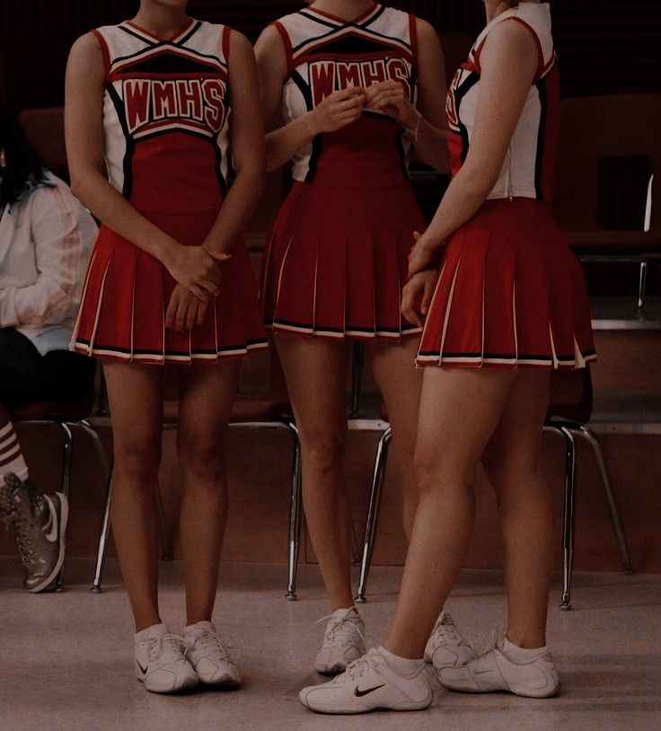 three girls in cheerleader outfits standing next to each other with their hands on their hips