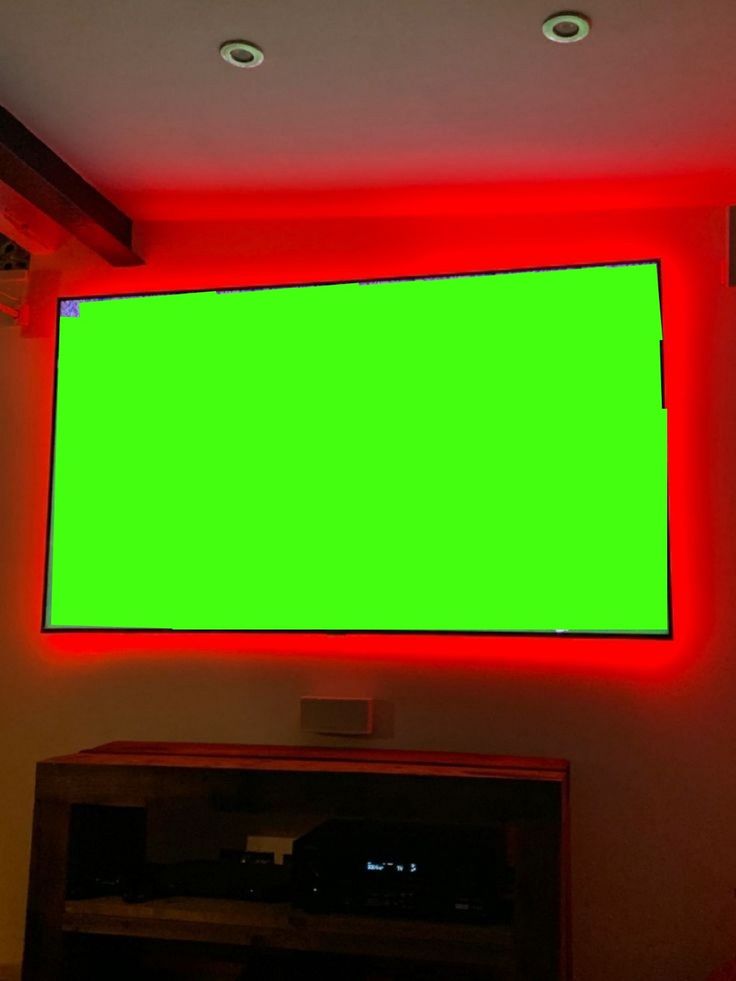 a flat screen tv sitting on top of a wooden entertainment center next to a neon green wall