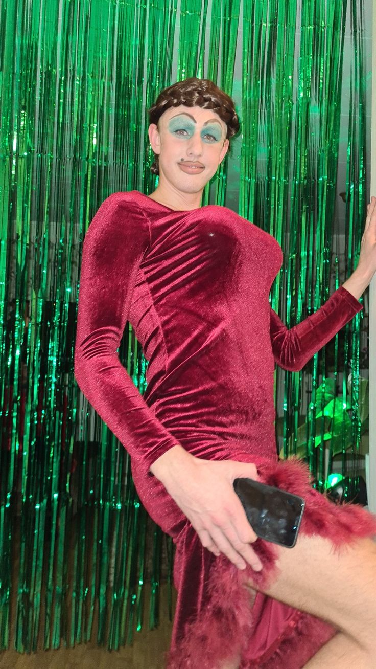 a woman in a red dress posing for the camera with green tinsel behind her