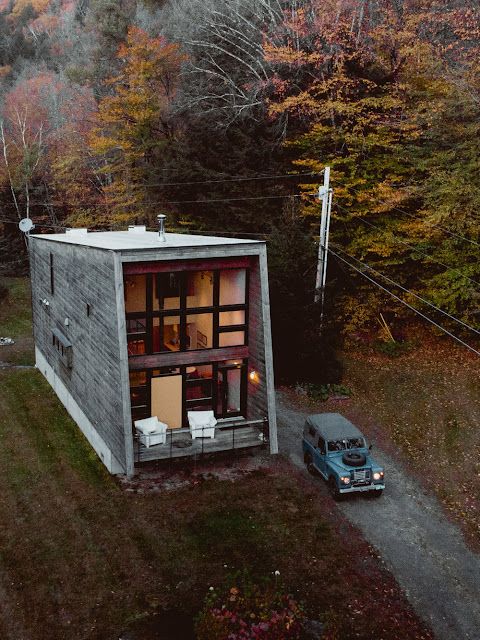 a car parked in front of a small house on the side of a hill with trees