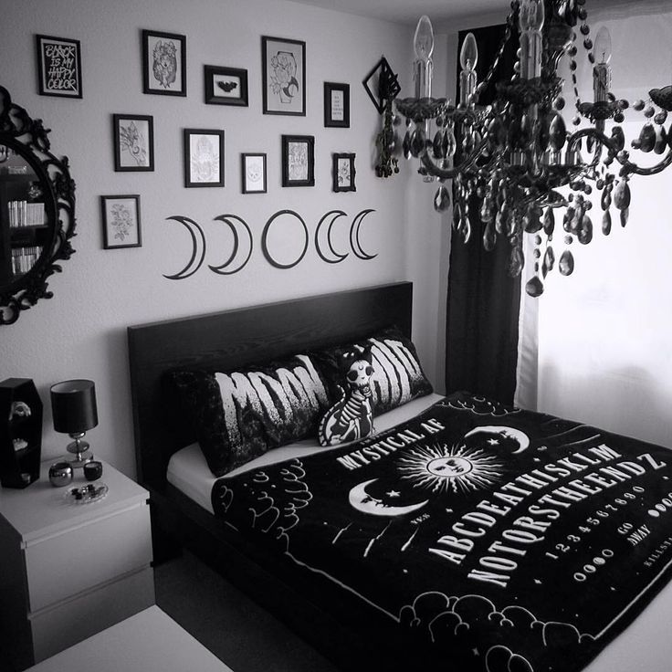 black and white photograph of a bedroom with bed, chandelier and pictures on the wall