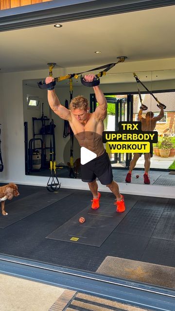 a man is doing exercises with his dog in front of the gym door while another dog looks on