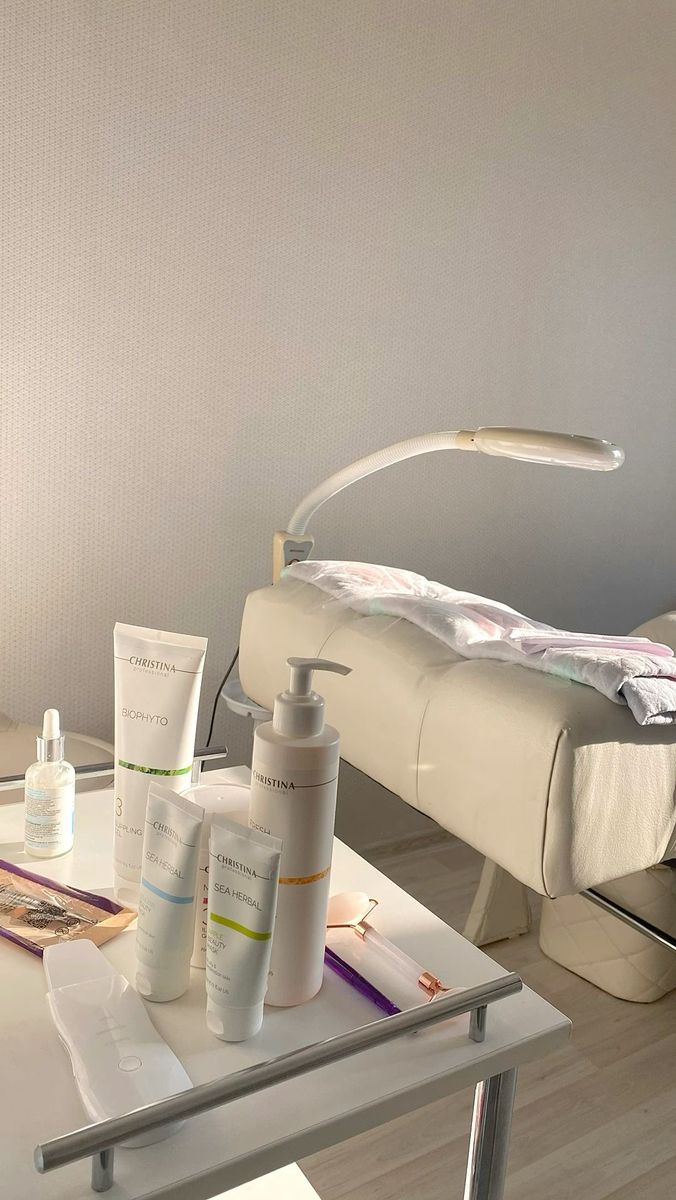 a white table topped with lots of personal care items next to a bed in a room