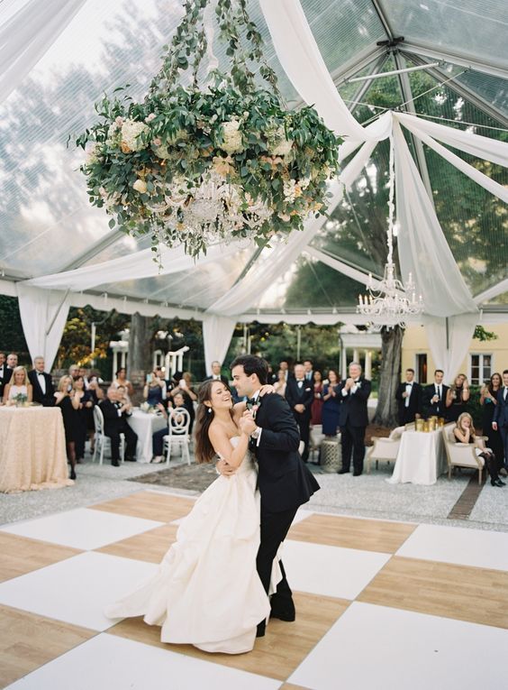 a bride and groom dance on the dance floor at their wedding reception in a tent