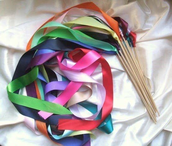 a bunch of colorful streamers on top of a white sheet next to a wooden stick