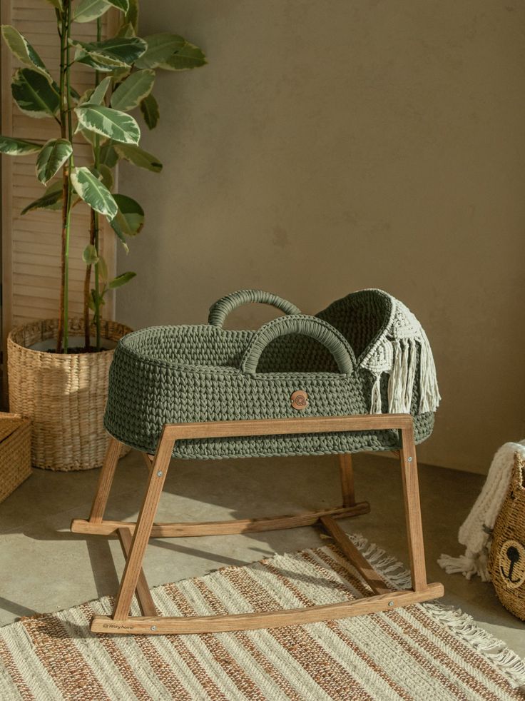 a wicker baby's pram in front of a potted plant and rug