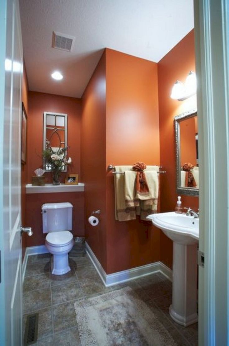 a bathroom with orange walls and white fixtures on the wall, along with a toilet and sink