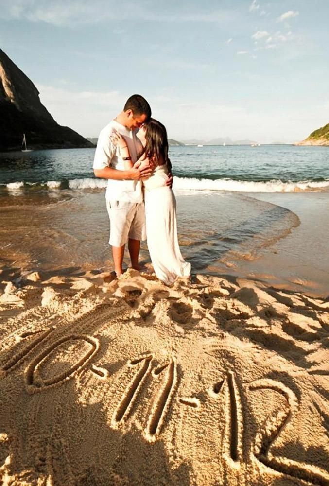 a man and woman standing in the sand with their arms around each other as they hug