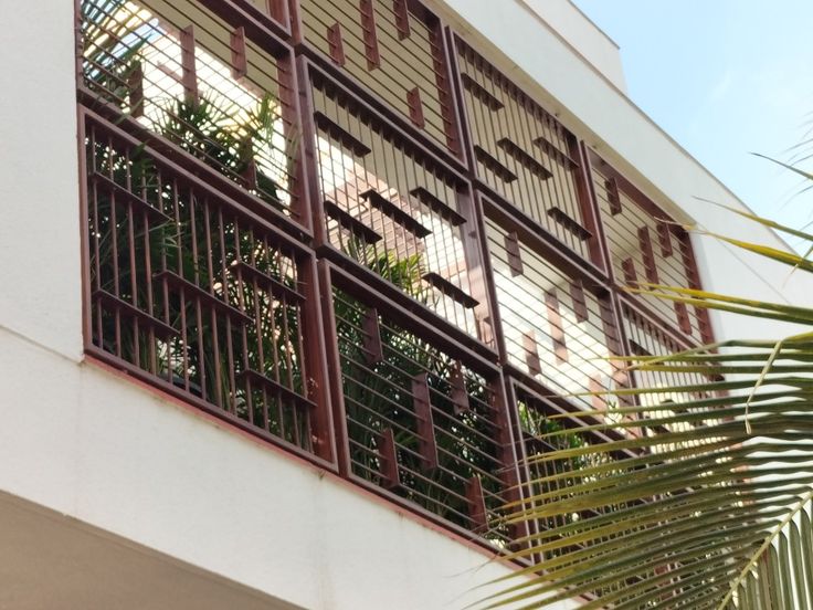 an apartment building with metal bars on the balcony and palm trees in the foreground