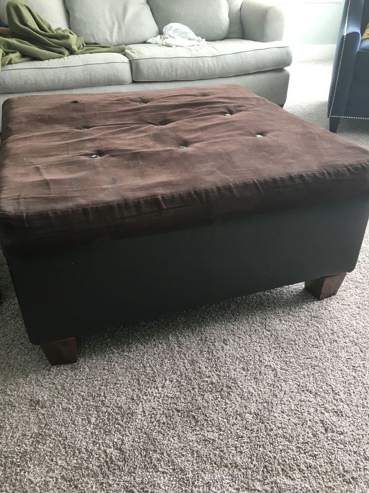 a brown ottoman sitting on top of a carpeted floor