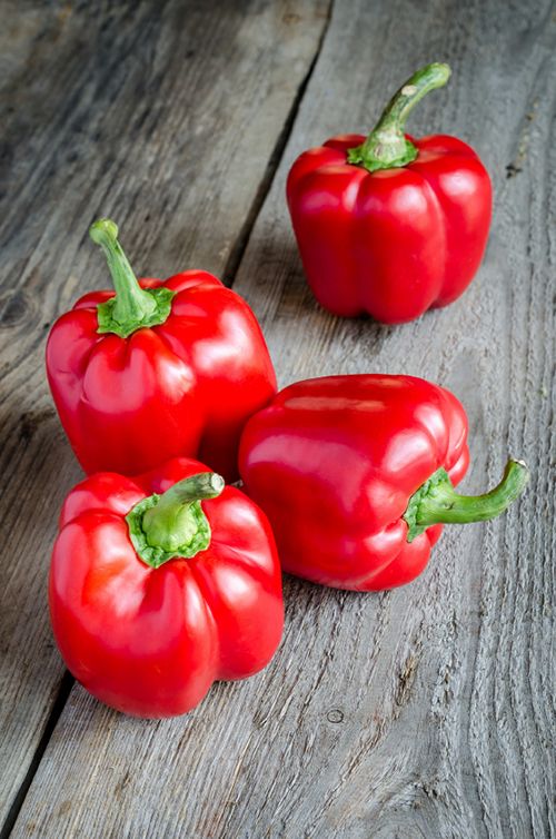 three red peppers sitting on top of a wooden table