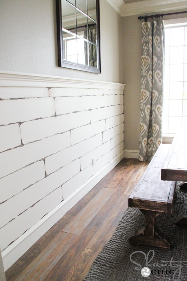 a wooden table sitting in front of a window next to a wall with a mirror on it