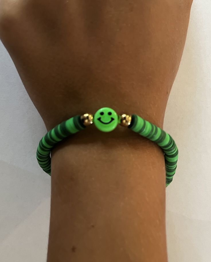 "Smiley Green", as Grace describes it, is one of her many bracelets she's making.  Clay beads are threaded onto high test fishing line tied together for a semi-stretch component, but don't pull too hard! 😜Green plastic smiley face for a fun look.  Very unique gift for any daughter, niece or granddaughter! Fun Adjustable Green Beaded Bracelets, Adjustable Green Playful Bracelets, Playful Green Adjustable Bracelets, Fun Green Stretch Bracelet For Friendship, Fun Green Beaded Bracelets For Friendship, Green Stretch Bracelet With Letter Beads In Fun Style, Fun Green Friendship Bracelets With Round Beads, Fun Green Round Beads Friendship Bracelets, Fun Green Stretch Bracelet With Letter Beads