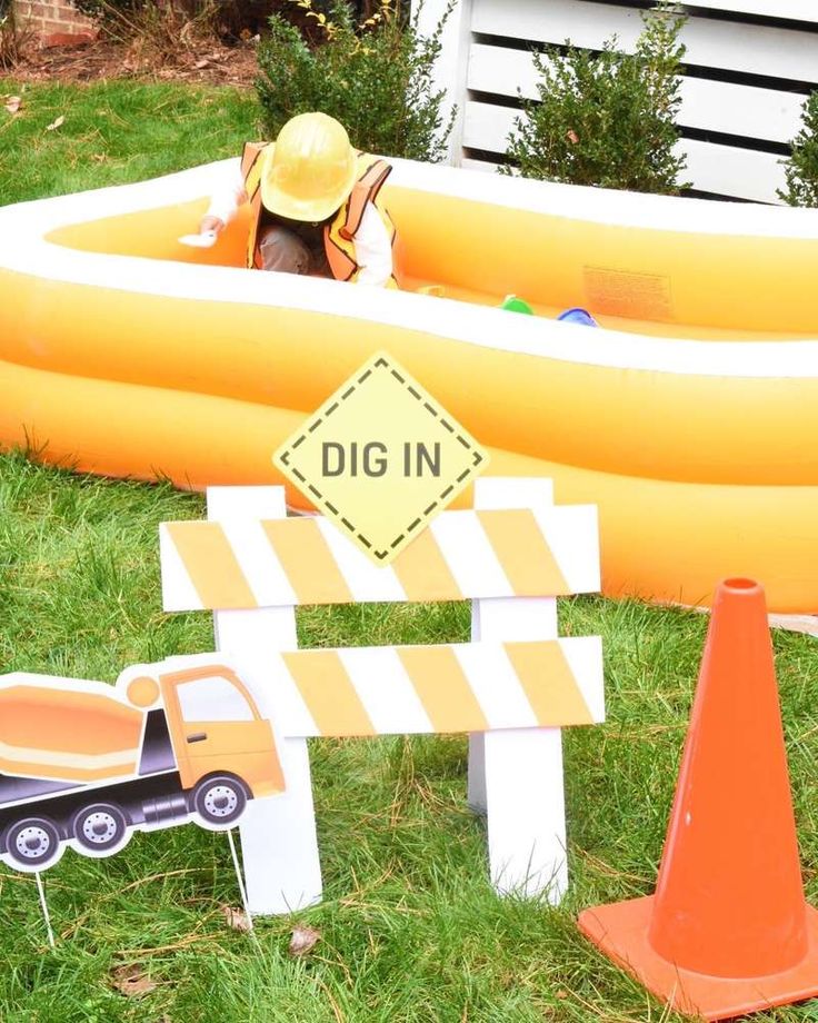 an inflatable raft and construction signs on the grass next to a sign that says dig in