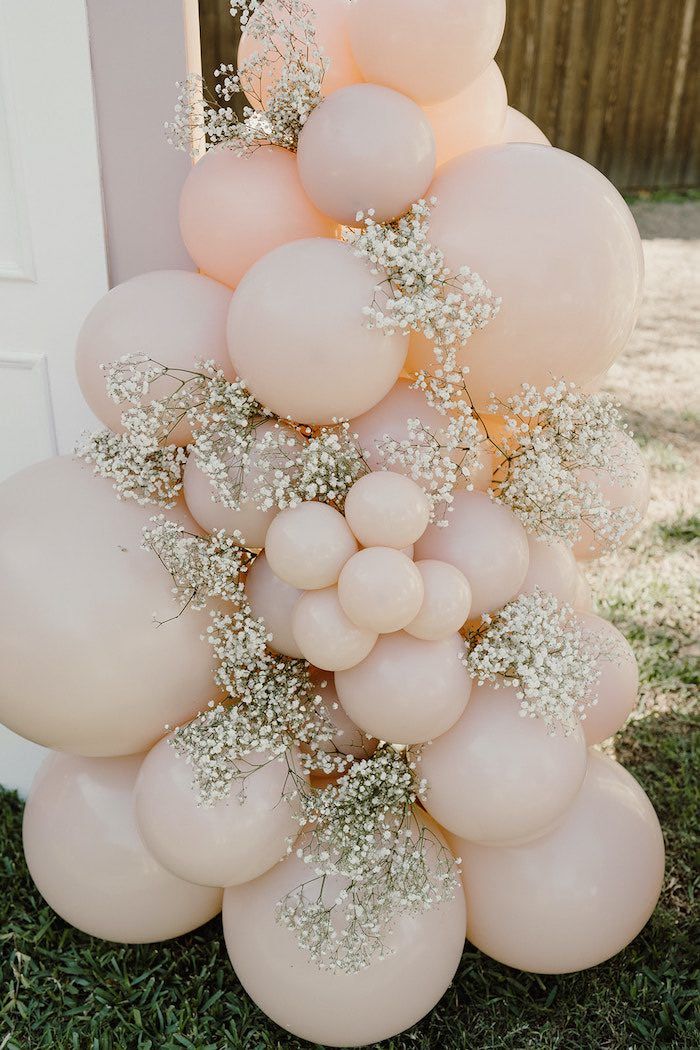 a bunch of balloons that are in the grass with some flowers on top of them