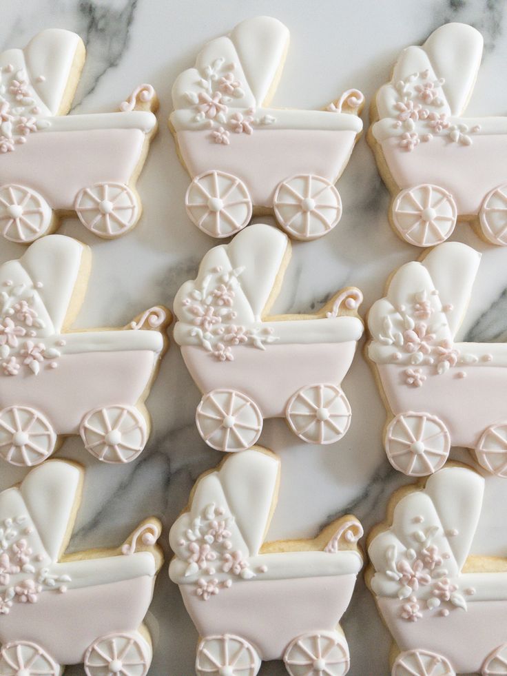 decorated cookies in the shape of baby's carriages on a marble countertop