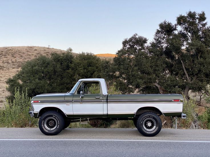 an old pickup truck is parked on the side of the road