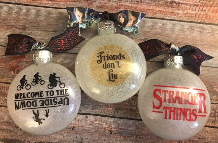 three christmas ornaments hanging on a wooden wall with ribbon around the top and saying friends don't lie