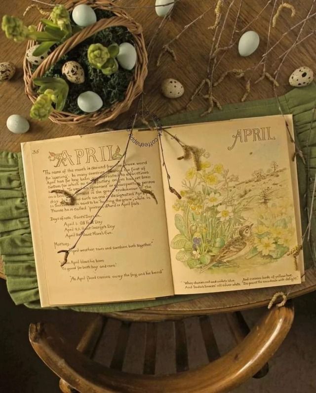 an open book sitting on top of a wooden table next to some eggs and flowers