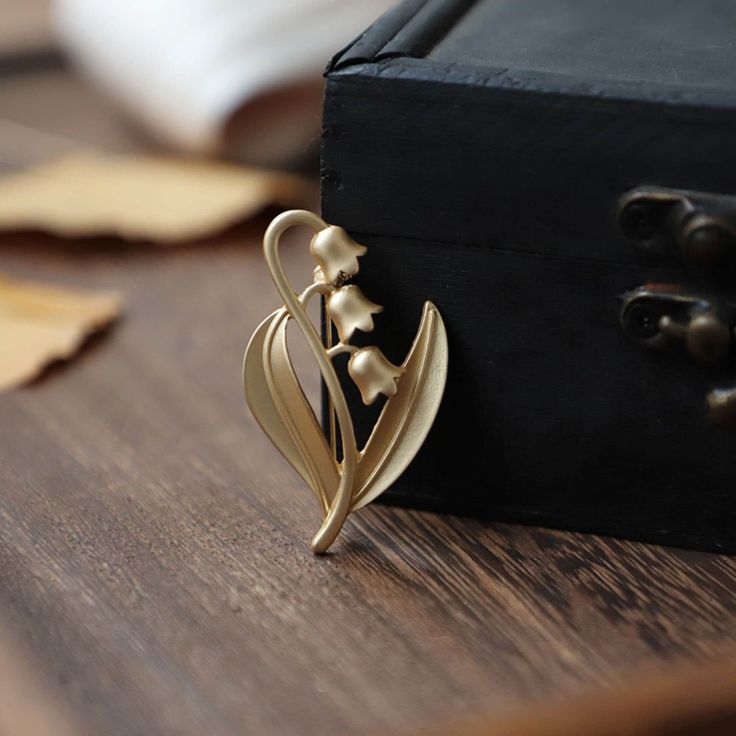 Show your unique style with this gorgeous Lily of the Valley Brooch. Delicately crafted from gold, this brooch is perfect for any occasion - from a casual day out to your wedding day. With eye-catching floral detail, this classy brooch will be sure to make a statement. 👌 M A T E R I A L • 18K Gold plated over brass• This product is hypoallergenic (nickel free) and tarnish resistant 📏 S I Z E • Length: 5.5 cm (2.16 inch)• Width: 3 cm (1.18 inch) Elegant Yellow Gold Enamel Pin Gift, Gold Flower Brooch Lapel Pin, Brass Brooch For Wedding, Brass Brooch Jewelry For Wedding, Brass Wedding Brooch, Wedding Enamel Pin Brooch, Elegant Gold Flower Lapel Pin, Wedding Yellow Gold Lapel Pin, Gold Flower Brooch Pins