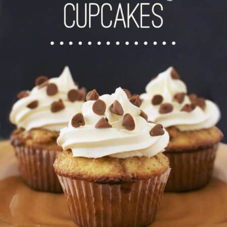 three cupcakes with white frosting and chocolate chips on top sitting on a plate