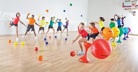 a group of children playing with balls in an indoor gym