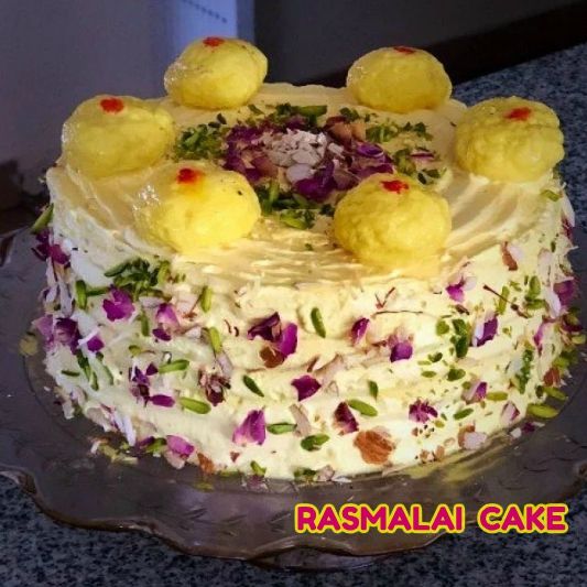 a cake with white frosting and purple flowers on top is sitting on a glass platter