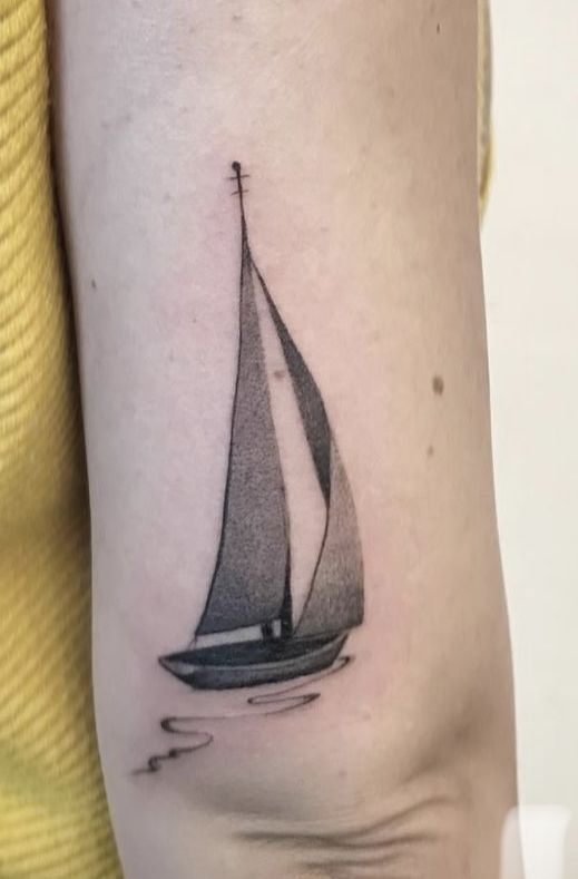 a black and white photo of a sailboat on the back of a woman's arm