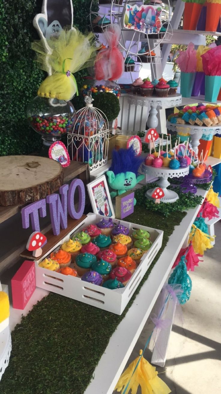 there are many items on the table at this birthday party, including cupcakes and candy