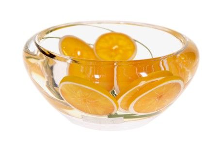 a glass bowl filled with oranges on top of a table