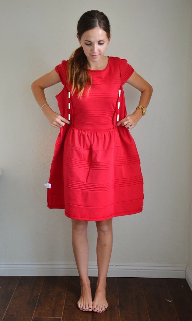 a woman standing in front of a wall wearing a red dress with pockets on it