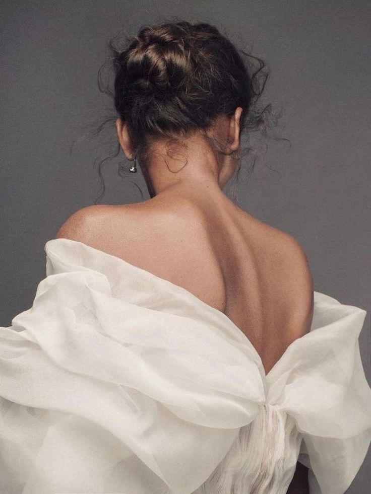 the back of a woman's white dress, with her hair in a bun