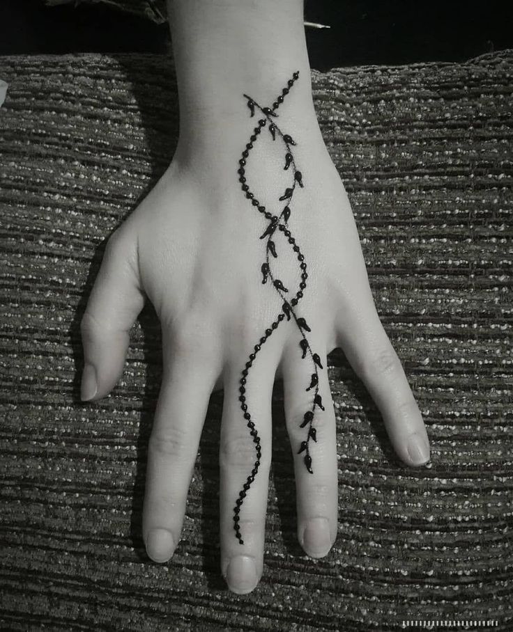 a person's hand with a black and white tattoo design on their left palm