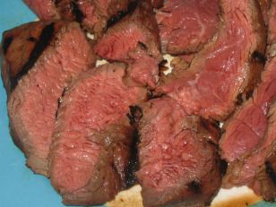 sliced meat on a blue plate sitting on a table