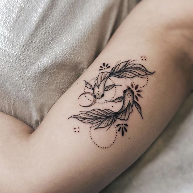 a woman's arm with a bird and leaves tattoo on the left side of her arm