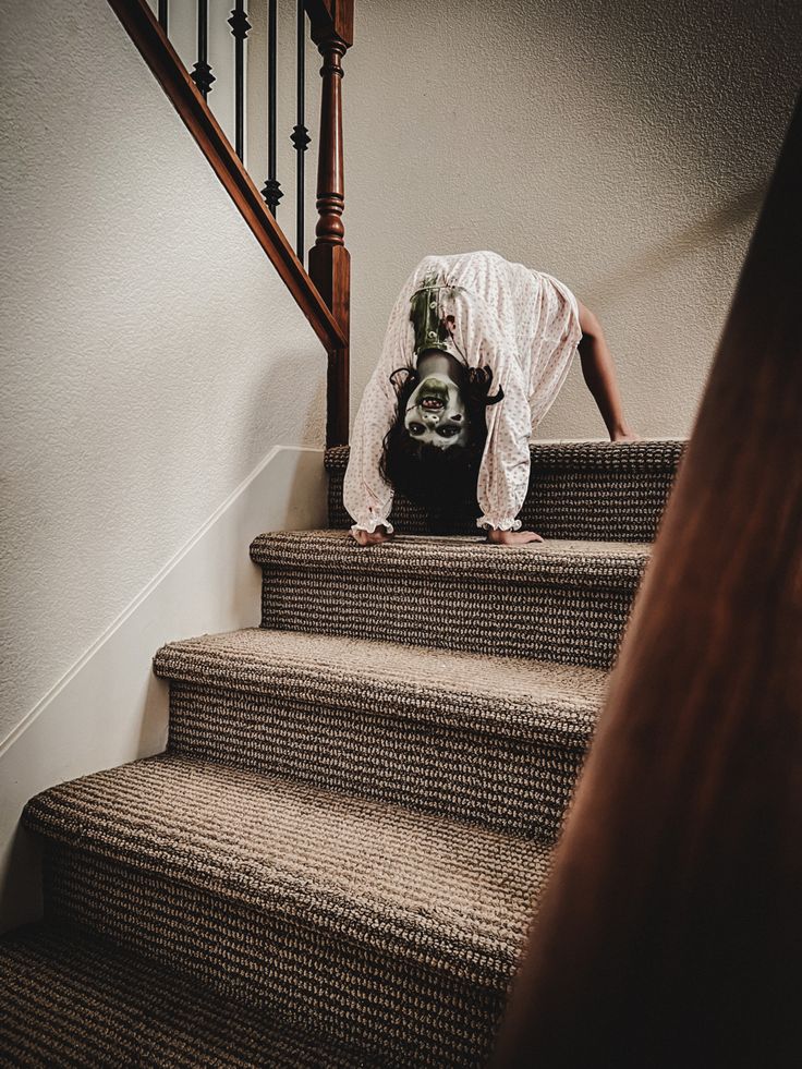 a woman with her head in the air on top of some stairs while wearing a skeleton mask