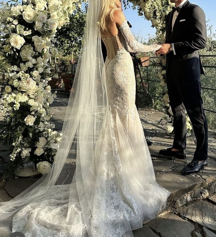 the bride and groom are getting married in front of an arch with flowers on it