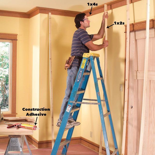 a man standing on a ladder working on the wall