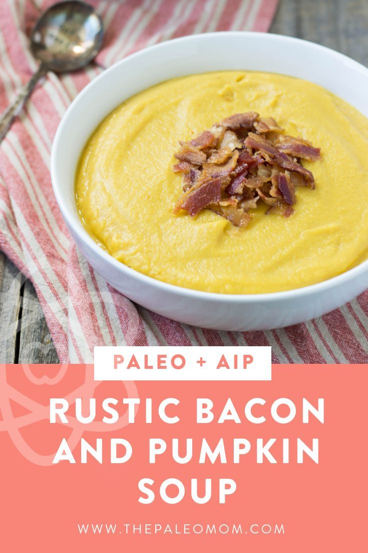 a white bowl filled with bacon and pumpkin soup on top of a striped table cloth