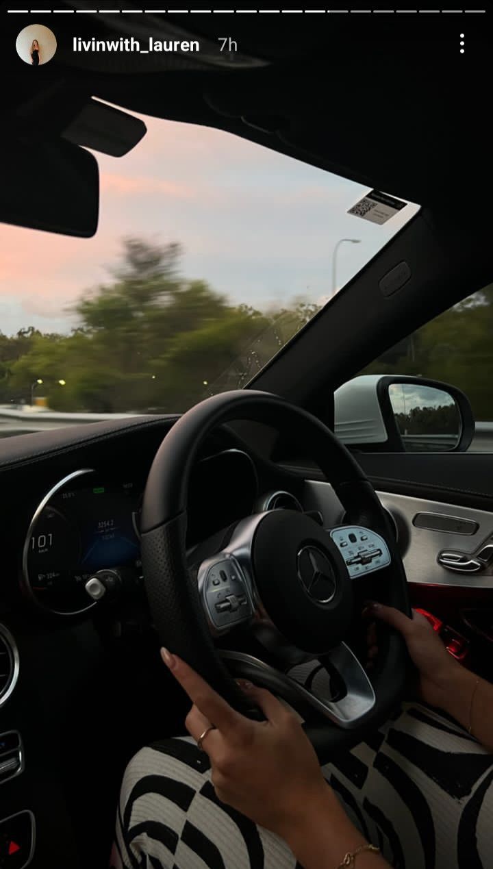 a woman is driving her car on the road