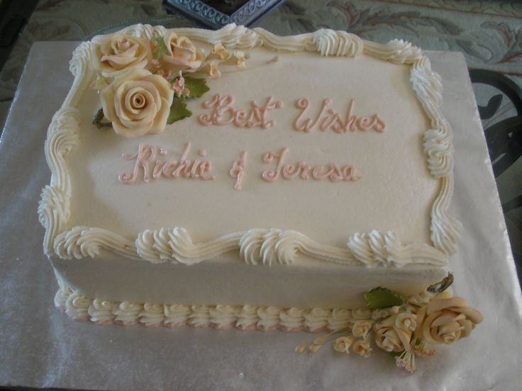 a cake with white frosting and pink flowers on the side that says best wishes india & teresa